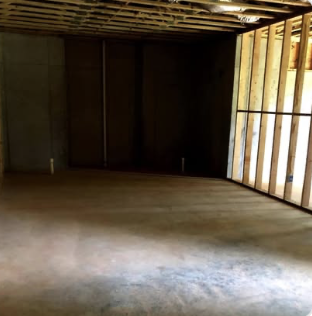Before: unfinished basement with exposed framing and concrete floor before renovation by Keystone South Construction
