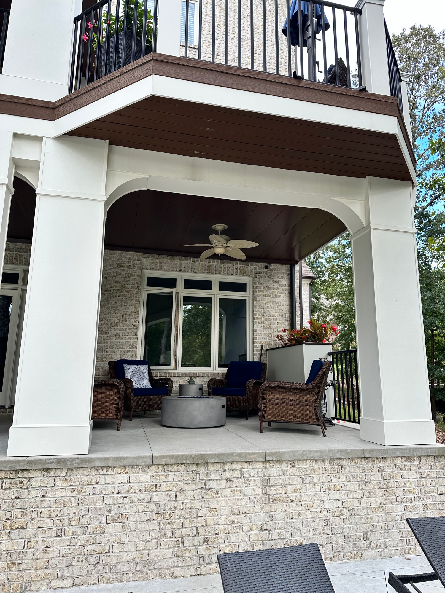 Lower level covered patio with arched columns and wicker furniture — Lake Lanier home by Keystone South Construction